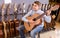 Teenage boy choosing best acoustic guitar in musical shop