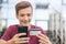 Teenage boy with a credit card and mobile phone makes purchasing outdoors. Happy young man is using smartphone and bank card for