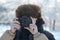 A teenage boy with curly long hair takes a picture with a digital SLR camera. Winter photo shoot outdoors