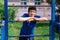 Teenage boy exercising outdoors, sports ground in the yard, he posing at the horizontal bar, healthy lifestyle