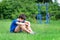 Teenage boy exercising outdoors, sports ground in the yard, he sits on the green grass of the playground, healthy lifestyle