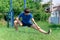 Teenage boy exercising outdoors, sports ground in the yard, he squats and does a warm-up, healthy lifestyle