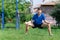 Teenage boy exercising outdoors, sports ground in the yard, he squats and does a warm-up, healthy lifestyle