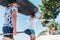 Teenage boy with father surfers carrying on the heads the stand-up paddleboard together with a paddle on the bright sunny day noon