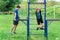 Teenage boy and girl exercising outdoors, sports ground in the yard, they posing at the horizontal bar, healthy lifestyle