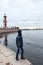 Teenage boy is on granite embankment of Neva river, near the Rostral Column with view at the Peter and Paul Fortress from water,