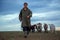 A teenage boy grazes goats in a field. A shepherd with goats in a field against a stormy sky.