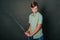 A teenage boy in a green T-shirt and jeans holds a medieval sword in his hands. Studio photo on a gray background