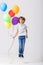 Teenage boy holding a bunch of balloons jumps in an empty room