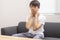 Teenage boy holding his hand behind his neck sitting on sofa at home.