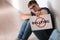 Teenage boy holding sheet of paper with word BULLYING while sitting on floor at school