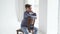 A teenage boy in a jacket and jeans poses on a chair by a window.