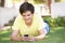 Teenage Boy Laying In Park Using Mobile Phone