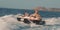 Teenage boy and little boy laughing whilst being pulled by a boat on an inflatable doughnut in the ocean at St tropez France