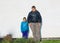 Teenage boy and little joyful happy girl standing against stucco old exterior house wall lighted by bright sunshine