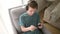 Teenage boy is playing a portable game console. A teenager sits in a chair in the living room and plays a gadget