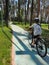 A teenage boy rides a bicycle in the park on a winding path in perspective. Rear view