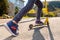 A teenage boy rides a scooter. Legs close-up. Bottom and side view. Empty street in Sunny weather in the background. Concept of