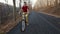 Teenage boy riding his bike on sunny autumn forest road downhill