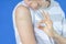 Teenage boy show to adhesive bandage plaster on his arm gesturing Okay after vaccination on blue background