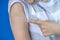 Teenage boy show to adhesive bandage plaster on his arm after vaccination on blue background. Injection covid vaccine