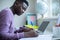 Teenage Boy Sitting At Desk Doing Homework Assignment On Laptop