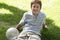 Teenage Boy Sitting In Lawn With A Ball