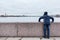 Teenage boy standing on granite embankment and looking at Peter and Paul Fortress across Neva river, Saint-Petersburg, Russia