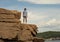 Teenage boy standing high on rugged rocks near Thunder Hole in Bar Harbor, Maine.