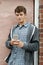 Teenage Boy Texting On Mobile Phone In Urban Setting