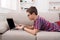 Teenage boy using laptop on couch at home