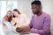 Teenage Boy Using Laptop At Home Whilst Girls Look At Mobile Phones In Background