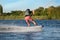 Teenage boy wakeboarding on river, back view. Extreme water sport