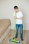 A teenage boy washes the floor and helps parents clean the children`s room. He is tired and does not want to get out