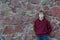 Teenage boy wearing burgundy hooded sweatshirt with vertical zipper leaning red granite boulders wall