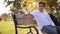 Teenage boy in white sweater sitting on the bench. Handsome school boy with backpack in autumn park