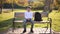 Teenage boy in white sweater sitting on the bench. Handsome school boy with backpack in autumn park