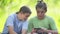 Teenage boys play on a smartphone in the park.