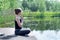 Teenage caucasian girl doing yoga exercise on the pond pier