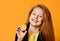 Teenage child in black jacket, yellow t-shirt. She smiling, holding half of lemon posing on orange background. Close up