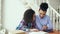 Teenage curly haired mixed race young girl sitting at the table concentrating focused learning lessons and her elder