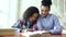 Teenage curly haired mixed race young girl sitting at the table concentrating focused learning lessons and her elder