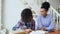 Teenage curly haired mixed race young girl sitting at the table concentrating focused learning lessons and her elder