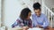 Teenage curly haired mixed race young girl sitting at the table concentrating focused learning lessons and her elder