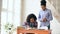 Teenage curly haired mixed race young girl sitting at the table concentrating focused learning lessons and her elder