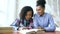 Teenage curly haired mixed race young girl sitting at the table concentrating focused learning lessons and her elder