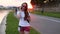 Teenage cute girl talking on mobile phone outdoors evening during sunset.