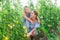 Teenage daughter helps mom look after tomato sprouts in garden