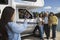 Teenage daughter photographing family with cell phone outside RV at lake