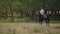 Teenage, farmer\'s son rides black horse in circle and prances on livestock farm on sunny day